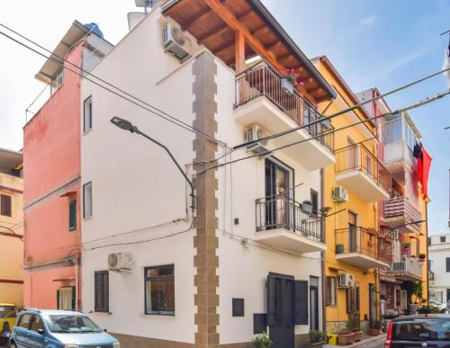 a white building with balconies and cars parked on a street at AMUNI' Apartments in Trabia