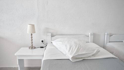 a white bedroom with a white bed and a table at Caldera View Resort - Adults Only in Akrotiri