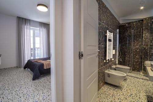 a bathroom with a sink and a toilet and a bed at Neva Suites Massa Lubrense Sorrento Coast in Massa Lubrense