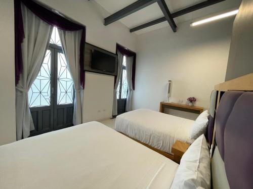 a hotel room with two beds and a window at Hotel Alhaja in Puebla