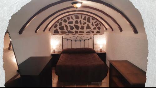 a bedroom with a bed and two nightstands with two lamps at CASA CUEVA LOS HONORIOS in Cortes de Baza