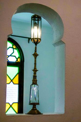 a lamp on a shelf with a stained glass window at Dar Tinjâa in Tangier