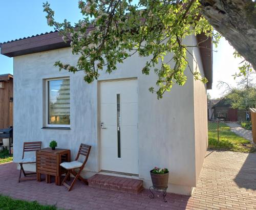 uma pequena casa branca com uma mesa e uma cadeira em SweetHome em Limbaži