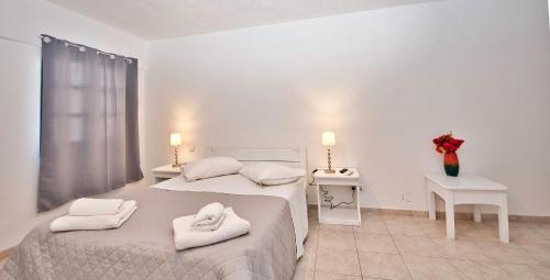 two beds in a white room with towels on them at Caldera View Resort - Adults Only in Akrotiri