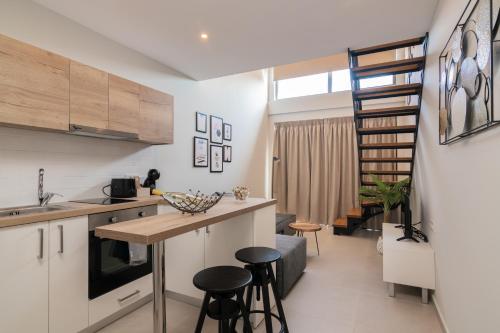 una cucina con bancone e sgabelli in una stanza di Bright & elegant loft suite in the city center a Città di Zante