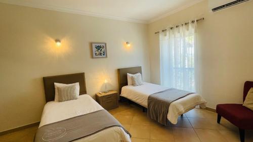 a room with two beds and a chair and a window at Santa Maria N by Check-in Portugal in Albufeira