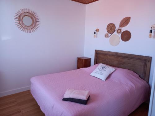 a bedroom with a pink bed with two towels on it at Les Crevettes in LʼÉpine