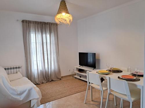 Una sala de estar blanca con una mesa y un televisor. en Oliveira Beach House, en Longueira
