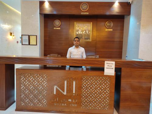 un hombre sentado en un escritorio en el vestíbulo en Nizwa Inn - نزوى إن en Nizwa