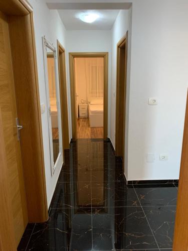 a hallway with a black tiled floor and a bathroom at Apartment Medjugorje Magnificat DeLuxe in Međugorje