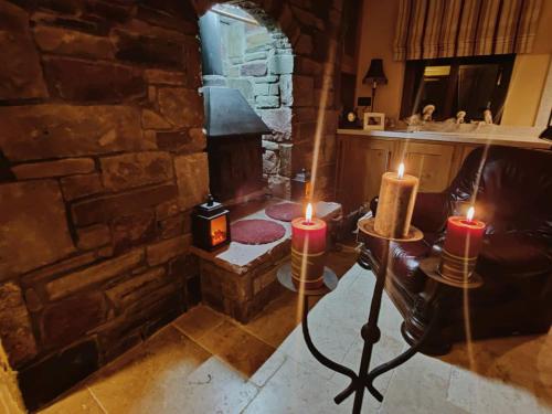 'Senán' Luxury Double Room في فوكسفورد: غرفة معيشة بها شمعتين وجدار حجري