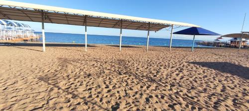 a sandy beach with an umbrella and the ocean at Квартира в Радуга WEST in Koshkolʼ