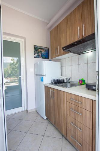 a kitchen with a white refrigerator and wooden cabinets at Vordos Rooms in Nea Vrasna