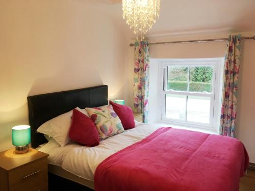 um quarto com uma cama rosa e uma janela em Feock beautiful sunny cottage em Truro