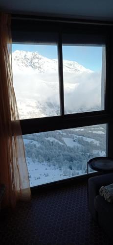 - une fenêtre dans une chambre avec vue sur les montagnes enneigées dans l'établissement Appartement St Lary Soulan pied des pistes (le Pla d’Adet) 5 personnes, à Saint-Lary-Soulan