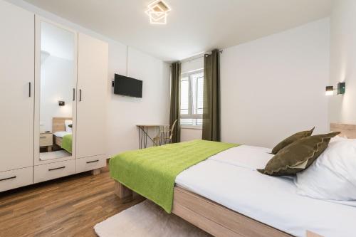 a white bedroom with a large bed and a mirror at Saluto al Sole in Zadar