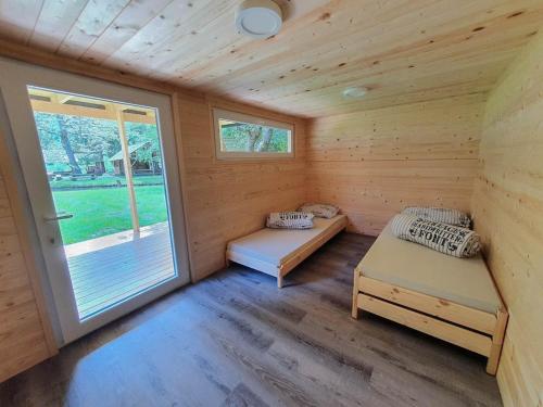 a log cabin with two beds and a window at Kamp na Otoku - Ljubno ob Savinji in Ljubno