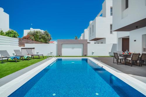 a pool with chairs and a table on a building at Stay in Style in Modern 3 Bedroom Villas Near Nissi Beach & Square in Ayia Napa