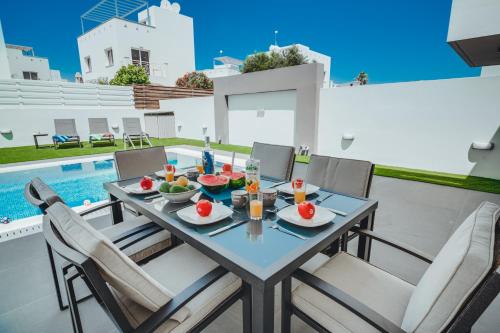 a table and chairs on a patio with a pool at Stay in Style in Modern 3 Bedroom Villas Near Nissi Beach & Square in Ayia Napa