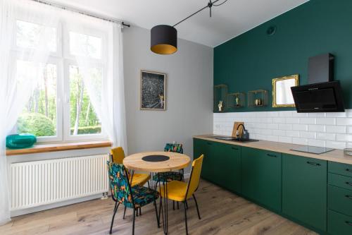 a kitchen with green cabinets and a table and chairs at Pasjonat Tu in Tuczno