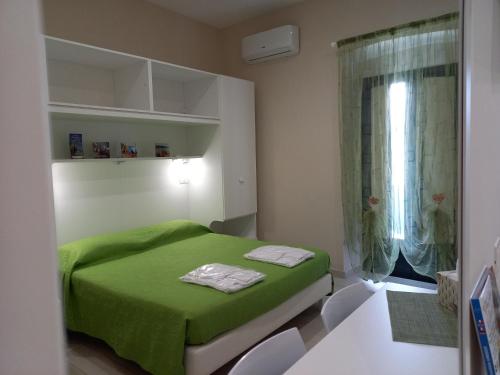 een slaapkamer met een groen bed en een raam bij M & M in Agropoli