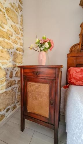 a table with a vase of flowers on it next to a bed at Kaya house in Nerežišća