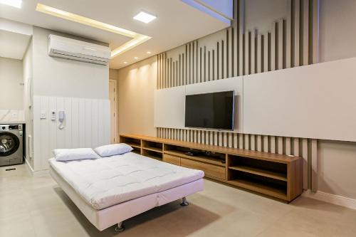 a large room with a tv and a bed at Apto novo com churrasq e piscina em Jurerê JPR201 in Florianópolis