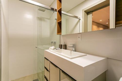 a white bathroom with a sink and a shower at Apto novo com churrasq e piscina em Jurerê JPR201 in Florianópolis