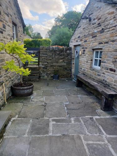 um pátio de pedra com uma parede de pedra e um edifício em Badgers Rest with free parking em Apperley Bridge