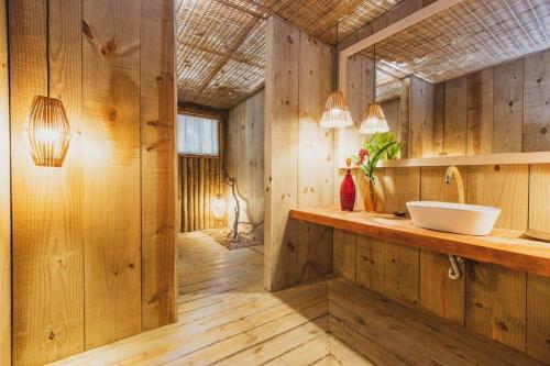 een badkamer met een wastafel en houten wanden bij Vila Botanika Caraíva in Caraíva