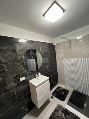 a bathroom with a sink and a mirror and a shower at Borșa ApartHotel 4 in Borşa