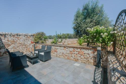 a patio with chairs and a stone wall at Masseria Giulio in Francavilla Fontana