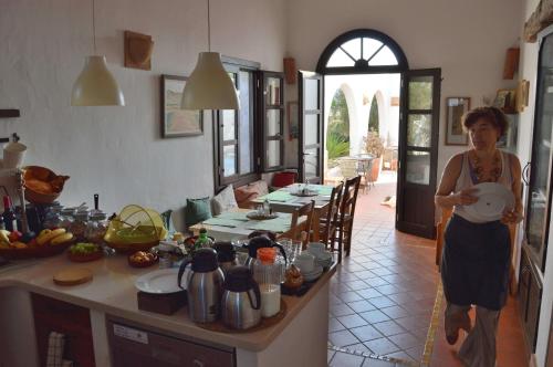 a woman standing in a kitchen holding a pot at Cortijo el Campillo in Los Albaricoques