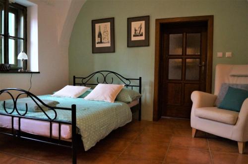 a bedroom with a bed and a chair at Olivea penzion & wine Mikulov in Mikulov