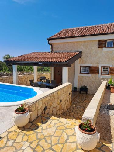 a house with a stone wall and a swimming pool at Villa Venkin Dvor in Novalja