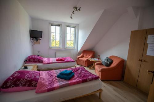 a attic room with two beds and two chairs at Gästehaus Wedework in Wedemark