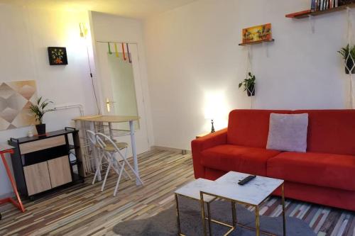 a living room with a red couch and a table at Cosy T1bis proche CentreVille, Petit Port, Audencia in Nantes