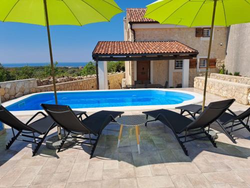 a table and chairs with umbrellas next to a pool at Villa Venkin Dvor in Novalja