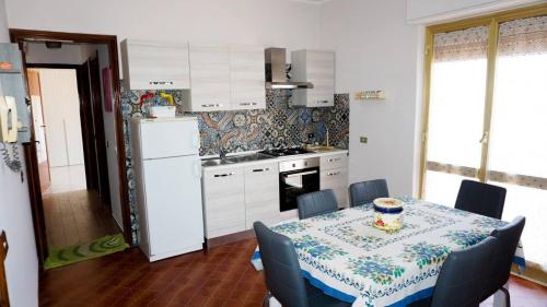 una cocina con mesa y sillas y una cocina con mesa y mesa. en Civico 177, en Avola