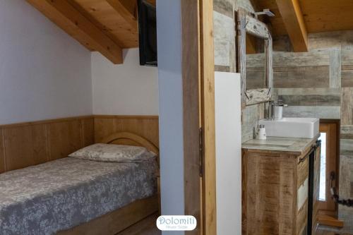 Dormitorio pequeño con cama y lavamanos en Dolomiti RiverSide, en Perarolo di Cadore