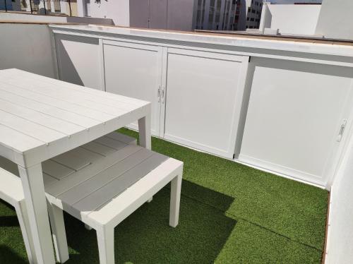 a white bench next to a table and a counter at La Terraza de Natipao in Rota