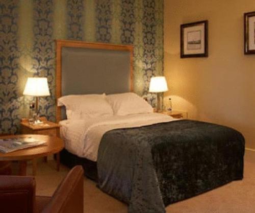a bedroom with a bed with two tables and two lamps at Farington Lodge Hotel in Preston