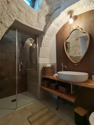 a bathroom with a shower and a sink and a mirror at Trullo La chicca della valle in Cisternino