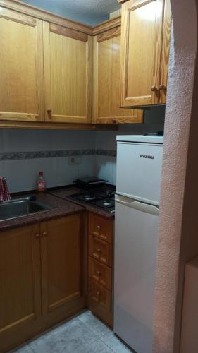 una cucina con frigorifero bianco e armadietti in legno di Apartment only 250m from the beach Los Locos a Torrevieja