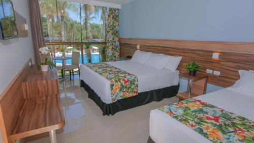 フォス・ド・イグアスにあるVivaz Cataratas Hotel Resortのベッド2台とテーブルがあるホテルの部屋