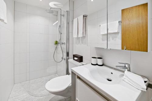 a white bathroom with a toilet and a sink at Apartment next to Titlis Station in Engelberg