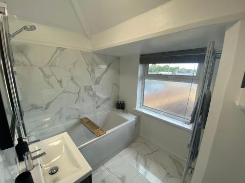 uma casa de banho branca com uma banheira e um lavatório em Coastal getaway in Heacham em Heacham