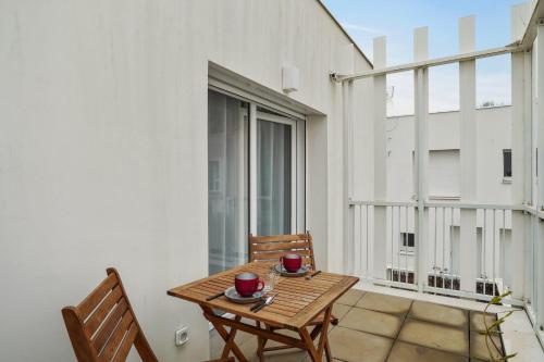 d'une table et de chaises en bois sur un balcon avec une fenêtre. dans l'établissement Bel appartement avec balcon à 100m de la mer à La Rochelle - Welkeys, à La Rochelle