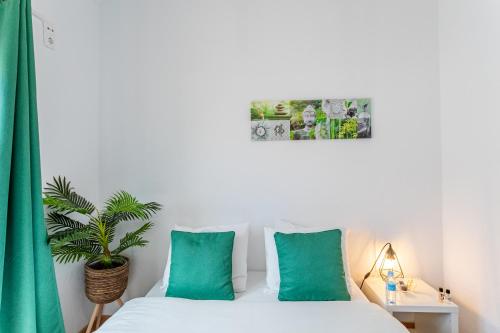 a bedroom with a bed with green pillows and a plant at Encarnação Home in Lisbon