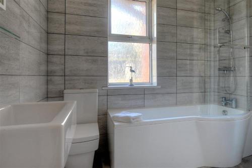 a bathroom with a tub and a toilet and a window at 2 Mareeba in Seaton